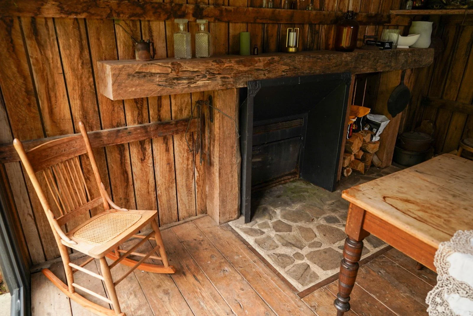 A stone fireplace glowing inside a timber cottage
