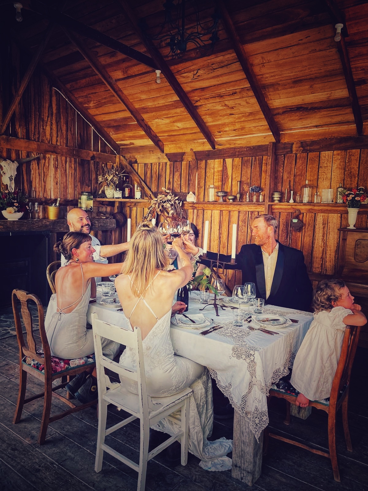 Wedding guests raising a toast around a long table inside The Barn