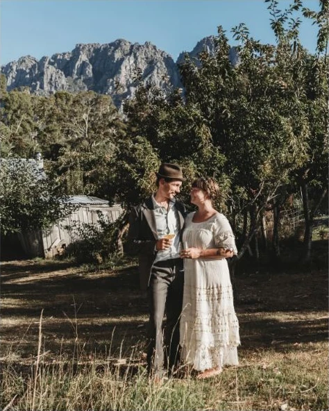 A newly married couple standing together beneath Mount Roland